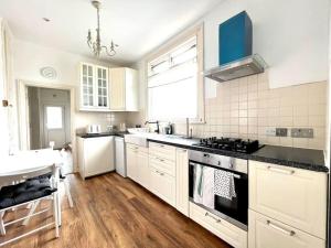 a kitchen with white cabinets and a stove top oven at Spacious 2-Bed House 20 mins from Central London in London