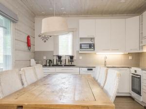 cocina con mesa de madera y armarios blancos en Holiday Home Sinisen tien helmi by Interhome, en Kannonkoski