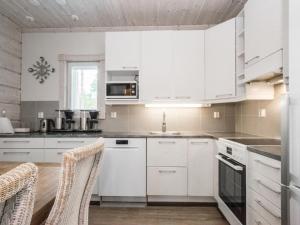 una cocina con armarios blancos y electrodomésticos blancos en Holiday Home Sinisen tien helmi by Interhome, en Kannonkoski