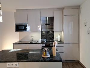 una cucina con armadi bianchi e piano di lavoro nero di Apartment Leon-2 by Interhome a Finkenberg