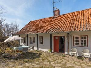 a house with a table and chairs and an umbrella at Holiday Home Asgot - 15m from the sea in Bornholm by Interhome in Hasle