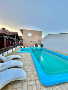 a swimming pool with two white chairs next to it at Complejo Sol Palmeras in Mar de Ajó