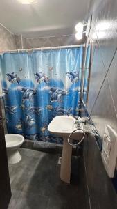 a bathroom with a sink and a dolphin shower curtain at Complejo Sol Palmeras in Mar de Ajó