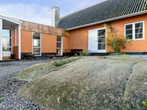 an orange house with a gravel driveway in front of it at Holiday Home Adrienne - 6-4km from the sea in Bornholm by Interhome in Åkirkeby