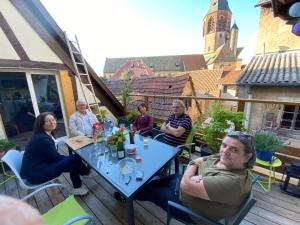 un gruppo di persone seduti a un tavolo su un patio di Joli 2 pièces et terrasse vue sur les toits en zone piétonne a Haguenau