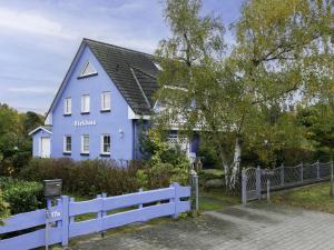 une maison bleue avec une clôture blanche devant elle dans l'établissement Apartment Eickhus Blaue Wohnung by Interhome, à Zinnowitz