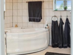 een badkamer met een wit bad en een zwarte handdoek bij Holiday Home Anemarie - all inclusive - 400m from the sea by Interhome in Karrebæksminde