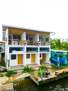 duas pessoas sentadas numa doca em frente a uma casa em Hotel Pura Natura Riverside Tortuguero em Tortuguero