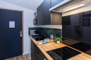 a kitchen with black cabinets and a wooden counter top at Le GreenStation-Gare-Hortillonnages-Centre Ville in Amiens +25 photos