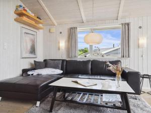 a living room with a black leather couch and a table at Holiday Home Sira - 350m from the sea in Funen by Interhome in Spodsbjerg