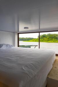 a bedroom with a large bed and a large window at Hotel Pura Natura Riverside Tortuguero in Tortuguero