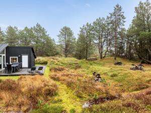 a small black house on a hill with a deck at Holiday Home Emila - 2-2km from the sea in Western Jutland by Interhome in Bolilmark