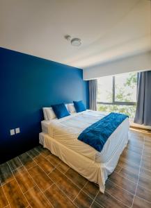 a blue bedroom with a large bed with blue walls at Entire Beautiful condo with rooftop pool and gym in Colonia San Benito