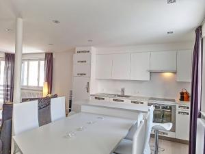 - une cuisine blanche avec une table et des chaises blanches dans l'établissement Apartment Violettes-Vacances A-B-C-7 by Interhome, à Crans-Montana