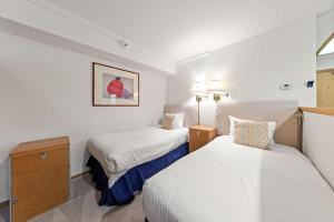 two beds in a small room with white walls at Palisades Tahoe Lodge Rentals Studio Loft #308 in Olympic Valley +11 photos