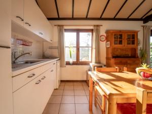 a kitchen with white cabinets and a wooden table at Holiday Home zeewind by Interhome in Bredene