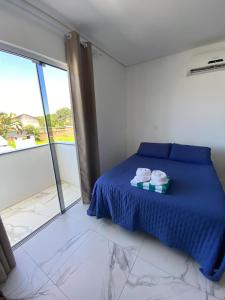 a bedroom with a blue bed and a large window at Pousada da Mel - Canasvieiras Floripa in Florianópolis