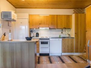 a kitchen with wooden cabinets and a white dishwasher at Holiday Home Teerenpesue e 37 by Interhome in Saariselka