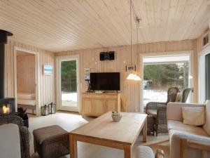 uma sala de estar com um sofá e uma televisão em Holiday Home Dwerg - 500m from the sea in NE Jutland by Interhome em Jerup