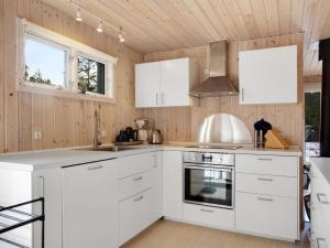 a kitchen with white appliances and wooden walls at Holiday Home Dwerg - 500m from the sea in NE Jutland by Interhome in Jerup