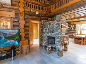 a living room with a stone fireplace in a log cabin at Holiday Home Menninkäisenkolo by Interhome in Äkäslompolo