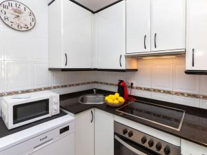 una cocina con armarios blancos, microondas y un bol de fruta en Villa Tres calas 2 by Interhome en L'Ametlla de Mar