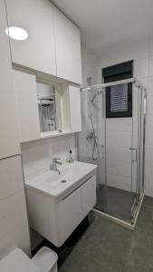 een witte badkamer met een wastafel en een douche bij Adria By The Sea - AB in Igalo