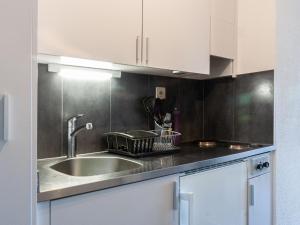 eine Küche mit einem Waschbecken und weißen Schränken in der Unterkunft Apartment Valaisia 24A by Interhome in Nendaz