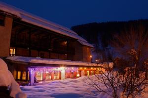 a building with christmas lights in the snow at night at Le Chalet Viso Auberge gite in Arvieux +36 photos