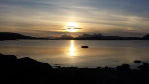 um pôr-do-sol sobre um corpo de água com montanhas em Base Camp Hamarøy em Sørkil