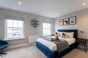 a bedroom with a blue bed and two windows at Elliot Oliver - Luxury Three Bedroom Town Centre Apartment With Parking in Cheltenham