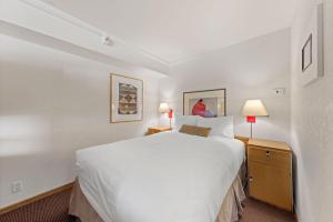 a bedroom with a large white bed and two lamps at Palisades Tahoe Lodge Rentals Studio Loft #314 in Olympic Valley +11 photos