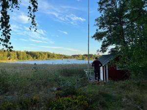 a man standing in front of a shed next to a lake at Summer House with Sauna on Beautiful Island 