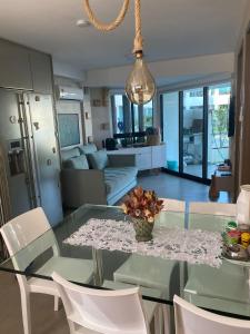 een eetkamer en een woonkamer met een glazen tafel en stoelen bij FLAT TAMANDARÉ MAUI 01 in Tamandaré