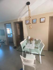 een eetkamer met een glazen tafel en witte stoelen bij FLAT TAMANDARÉ MAUI 01 in Tamandaré