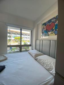 een slaapkamer met een groot wit bed met een raam bij FLAT TAMANDARÉ MAUI 01 in Tamandaré