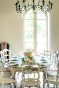 einen Esstisch mit Stühlen und einem Kronleuchter in der Unterkunft Château de Sienne proche Avignon Orange 7 Chambres Piscine Rivière in Chusclan