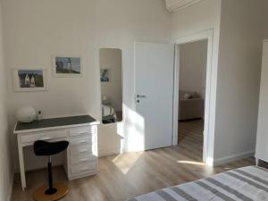 a white bedroom with a desk and a mirror at casa Fioravanti in Bologna