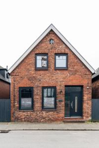 a red brick building with black windows on a street at Charmantes Stadthaus in Husum