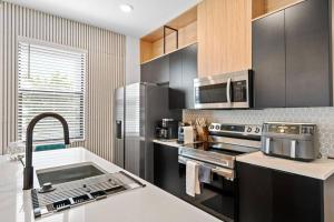 una cocina con electrodomésticos de acero inoxidable y fregadero en Luxury Townhouse All Suite Near Disney Universal, en Kissimmee