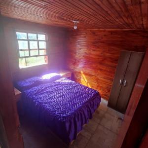 een slaapkamer met een paars bed in een houten kamer bij Cabaña El Mar in Barra del Chuy
