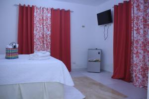 um quarto com cortinas vermelhas e uma cama com televisão em R.G sol 2 em Pantoja