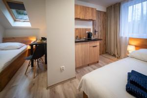 ein Hotelzimmer mit 2 Betten, einem Tisch und einer Küche in der Unterkunft Pokoje Vik-House in Wisła
