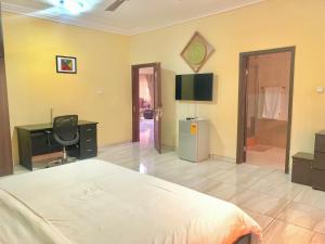 Dormitorio con cama, escritorio y TV en Royals 2 bedrooms Luxury en Accra