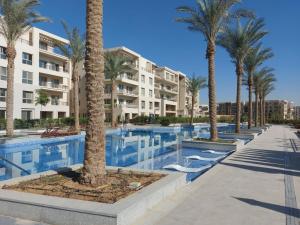 a swimming pool with palm trees in front of a building at Alumia Marigold Suite 3BR Apt Pool Access in Cairo