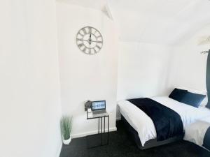 a bedroom with a bed and a clock on the wall at Watford Central Luxury Serviced Accommodation in Watford