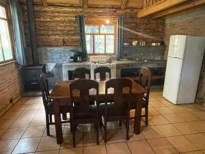 eine Küche mit einem Tisch und Stühlen sowie einem Kühlschrank in der Unterkunft Tranquila Cabaña en la Sierra - Parque La Pirámide 