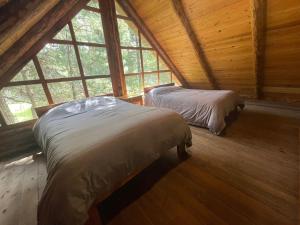 2 Betten in einem Zimmer mit einem großen Fenster in der Unterkunft Tranquila Cabaña en la Sierra - Parque La Pirámide 