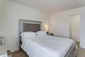 a white bedroom with a large bed with white sheets at Spacious Home with Patio Near Denver Airport in Aurora