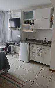 Una cocina con gabinetes blancos y un fregadero y una mesa. en B1415 Flat próx a esplanada dos ministérios, en Brasilia
